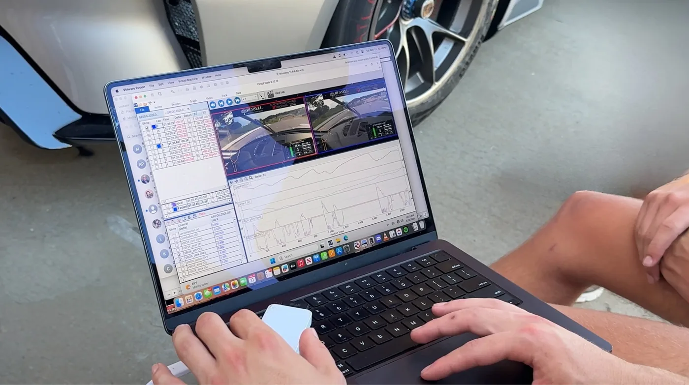 Lap time deltas and telemetry traces reviewed on a laptop beside the car